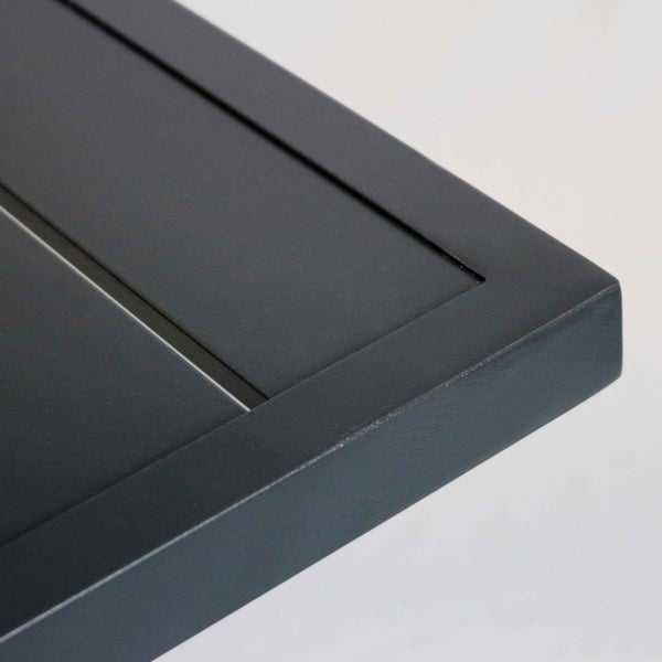 Eckdetail eines anthrazitfarbenen Gartenmoebelstuecks mit Lamellenstruktur aus Metall.