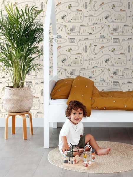 Kindertapete mit Straßen und Autos Motiv in einem Kinderzimmer mit weißem Bett und Holzpflanzenhocker.
