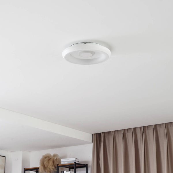 Runde LED-Deckenleuchte in Weiß mit konzentrischem Ringdesign, montiert an einer Zimmerdecke neben beigefarbenen Vorhängen.