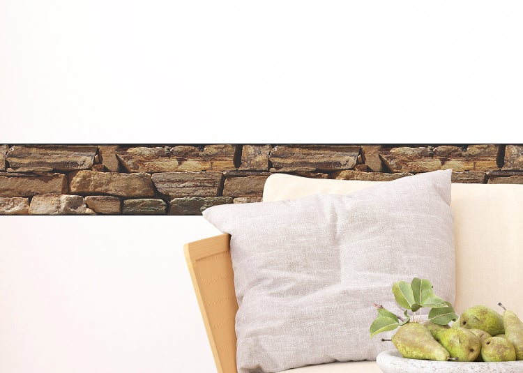 Tapetenbordüre mit Steinoptik als Wandgestaltung in einem Wohnzimmer mit Sessel und Kissen.