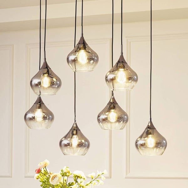 Siebenflammige Pendelleuchte mit rauchfarbenen Glasschirmen in Tropfenform, an schwarzen Kabeln in verschiedenen Höhen abgehängt.