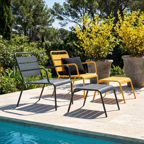 Moderne Gartenstühle und Fußhocker aus Metall mit Latten-Design auf einer Terrasse am Pool, umgeben von Pflanzen.