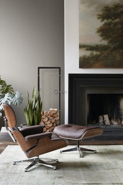 Wohnzimmer mit Sessel, Hocker, Kamin und Dekorationen für ein gemütliches Ambiente