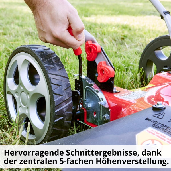 Nahaufnahme einer Person, die die zentrale 5-fache Höhenverstellung eines Rasenmähers bedient, der im Gras steht.