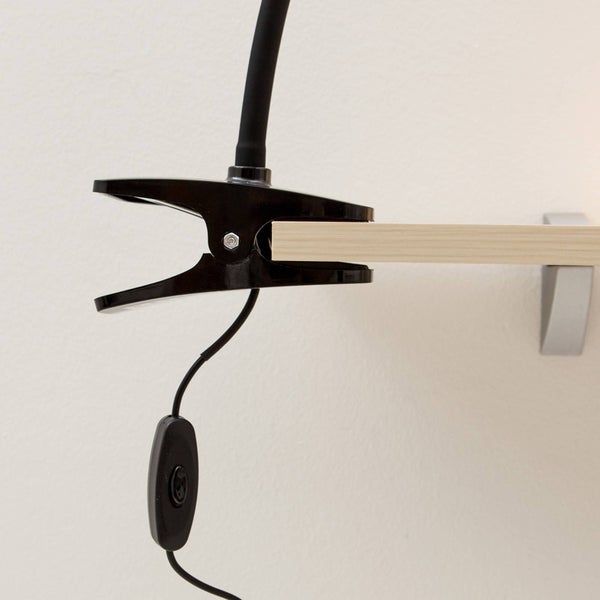 Schwarze Klemmleuchte befestigt an einem Regalboden mit Schnurschalter.