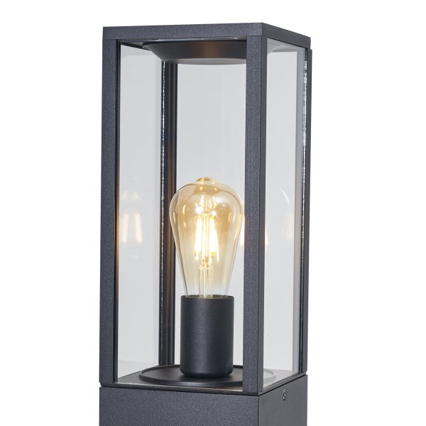 Moderne rechteckige Außenstandleuchte in Dunkelgrau mit Glaseinsätzen und einer sichtbaren Filament-Glühbirne.
