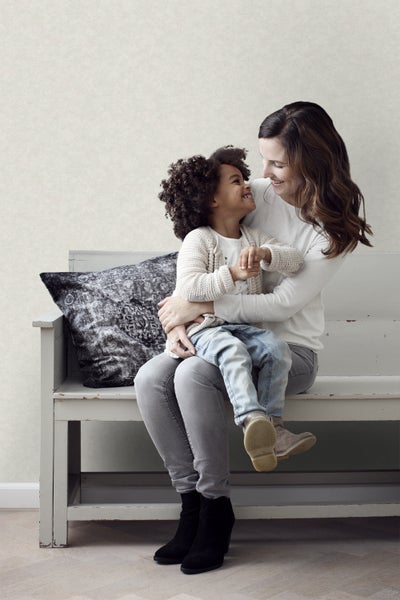 Mutter und Kind sitzen auf einer Bank vor einer Tapete.