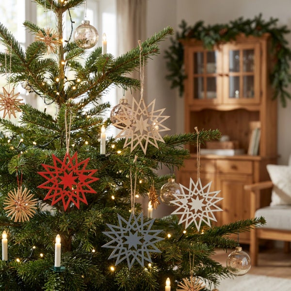 Weihnachtsbaum geschmückt mit hängenden Holzsternen und Glaskugeln in einem gemütlich eingerichteten Wohnraum