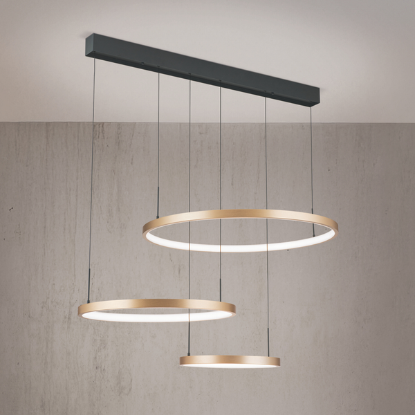 Moderne LED Pendelleuchte mit drei runden Ringen in goldener Optik an einer rechteckigen Deckenhalterung montiert.