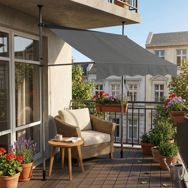 Graue Klemmmarkise auf einem hellen Balkon mit Rattansessel, Holztisch und Topfpflanzen.