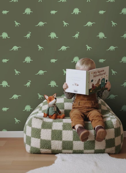 Kind liest Buch auf Sessel mit Dinosaurier-Tapete