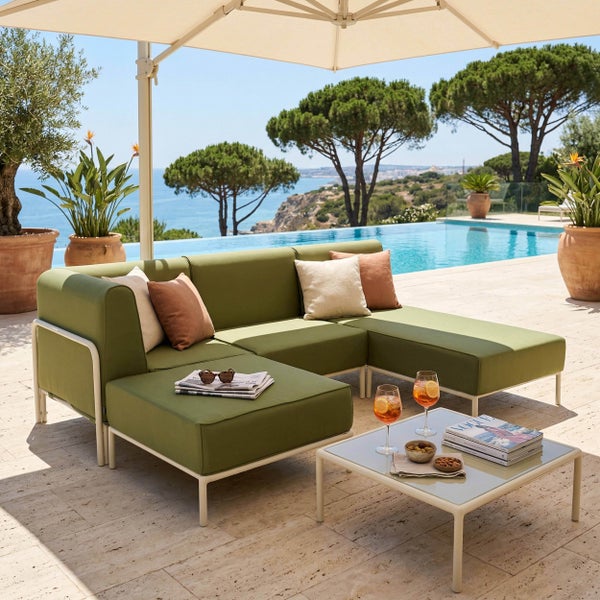 Moderne Gartenlounge aus grünem Stoff und hellem Metallgestell mit Couchtisch auf einer Terrasse am Pool mit Meerblick.