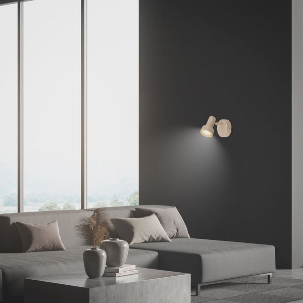 Moderner Wandstrahler in einem hellen, minimalistischen Wohnzimmer mit grauem Sofa, Couchtisch und großem Fenster.