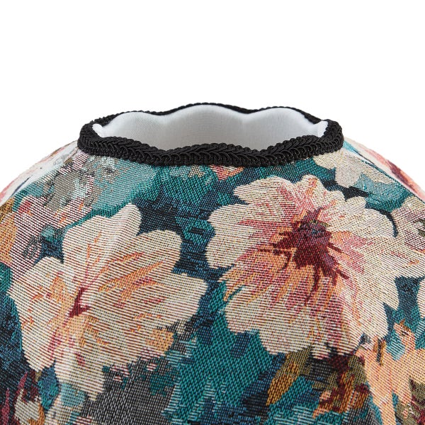 Nahaufnahme eines Textils mit Blumenmuster und schwarzer geflochtener Borte am Rand.