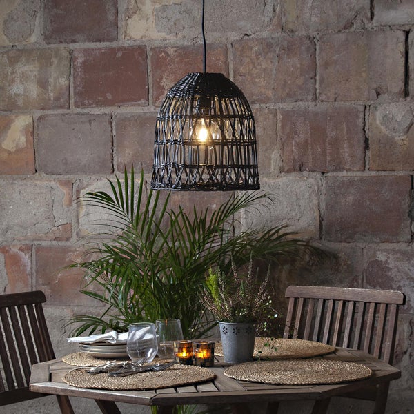 Szene mit einem Esstisch mit Geschirr und einer hängenden Rattanlampe