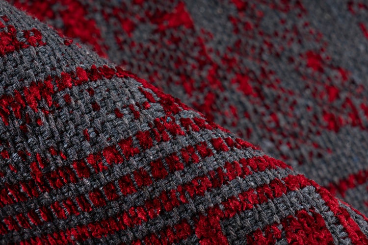 Detailansicht eines gewebten Teppichs mit strukturierter Oberfläche in Grau und Rot.