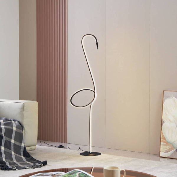 Moderne LED Stehlampe mit schwarzem geschwungenem Design in einem hellen minimalistischen Wohnzimmer neben einem Sofa.