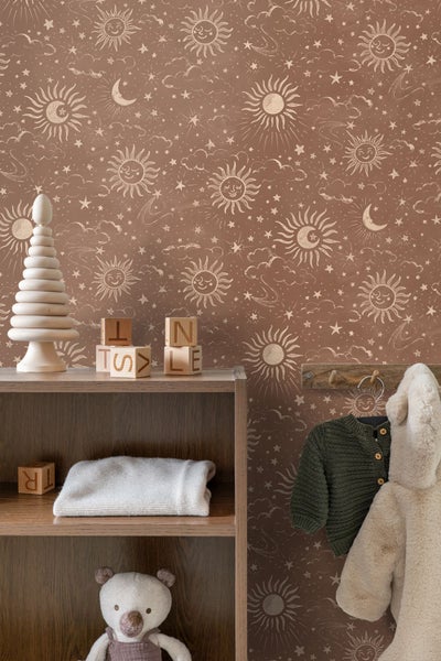 Braune Kindertapete mit Mustern von Sonne, Mond und Sternen hinter einem Holzregal mit Spielzeug und Kleidung in gemütlicher Atmosphäre.