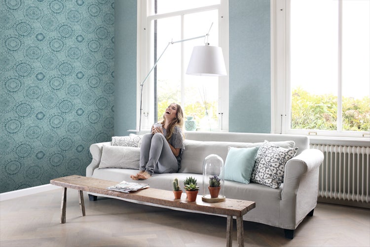 Wohnzimmer mit gemusterter Tapete, Sofa, Stehlampe und Holztisch