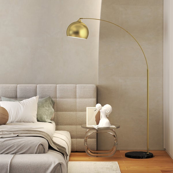 Goldfarbene Bogenstehlampe mit Marmorfuss in einem modern eingerichteten Schlafzimmer neben einem Bett.