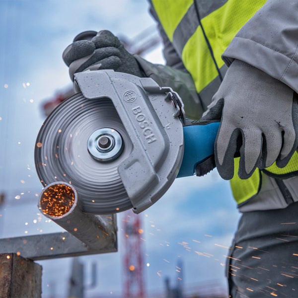 Bosch Winkelschleifer schneidet ein Metallrohr mit Funkenflug, geführt von einer Person in Arbeitskleidung mit Schutzhandschuhen.