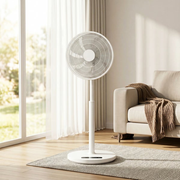 Moderner weißer Standventilator in einem hellen Wohnzimmer mit hellem Holzboden, Sofa und großen Fenstern mit hellen Vorhängen.