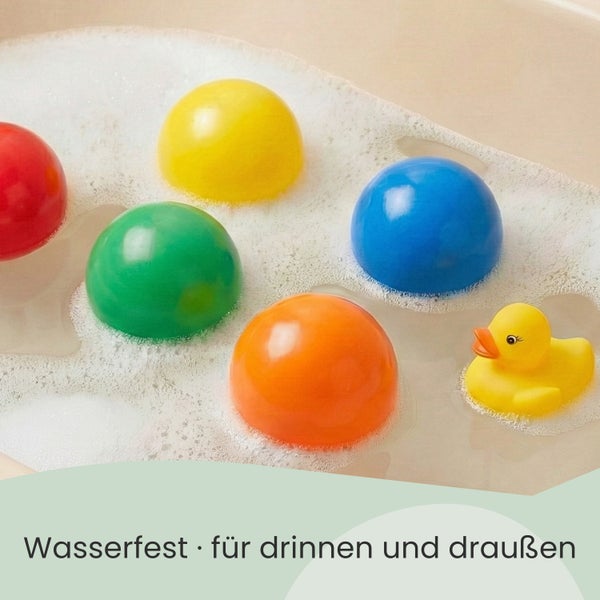 Bunte Spielbälle aus Kunststoff und eine Badeente schwimmen in Wasser mit Schaum. Wasserfestes Spielzeug für drinnen und draußen.
