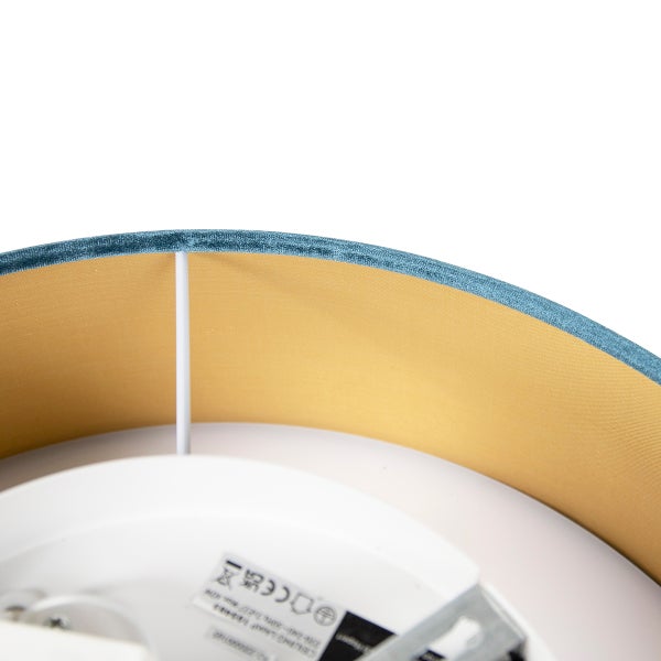 Detail eines runden Lampenschirms mit blauem Samtbezug und goldfarbener Innenseite.