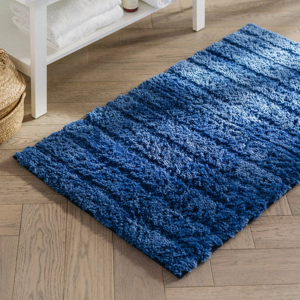 Blauer Badteppich auf Holzboden in Badezimmernähe