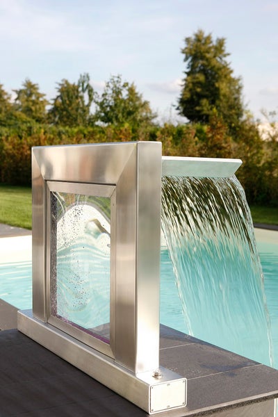 Moderne Schwalldusche für den Pool aus Edelstahl und Glas mit fließendem Wasserstrahl am Beckenrand.