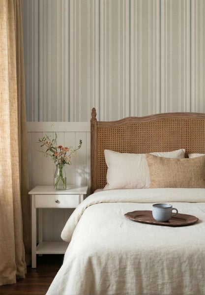 Schlafzimmer mit gestreifter Tapete, Rattanbett und weißem Nachttisch in natürlichem Einrichtungsstil mit heller Textiloptik.