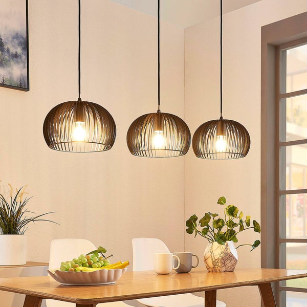 Drei Pendelleuchten aus Metall über einem Esstisch