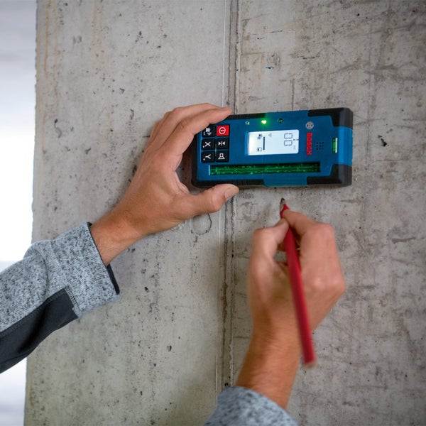Mann benutzt Bosch Ortungsgerät an Betonwand mit Bleistift um eine Markierung zu setzen.