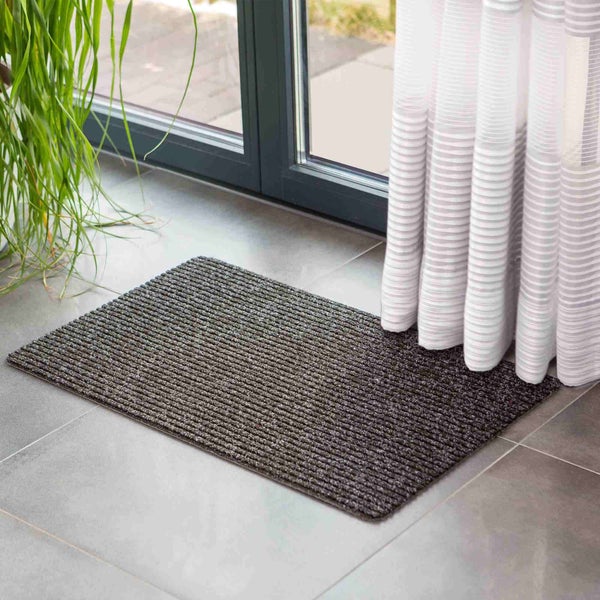 Fußmatte vor einer Terrassentür mit Vorhang und Pflanze