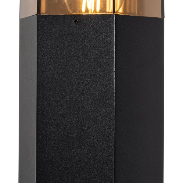 Detailansicht einer schwarzen Außenleuchte mit strukturierter Oberfläche, bernsteinfarbenem Glas und sichtbarem Leuchtmittel.