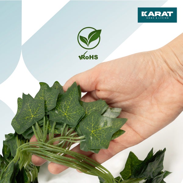 Künstliche Efeublätter in einer Hand gehalten. Karat Home & Living Logo. Beschränkung gefährlicher Stoffe.