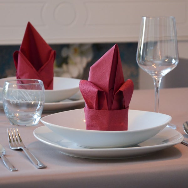 Gedeckter Tisch mit Tellern, Gläsern und gefalteten Servietten