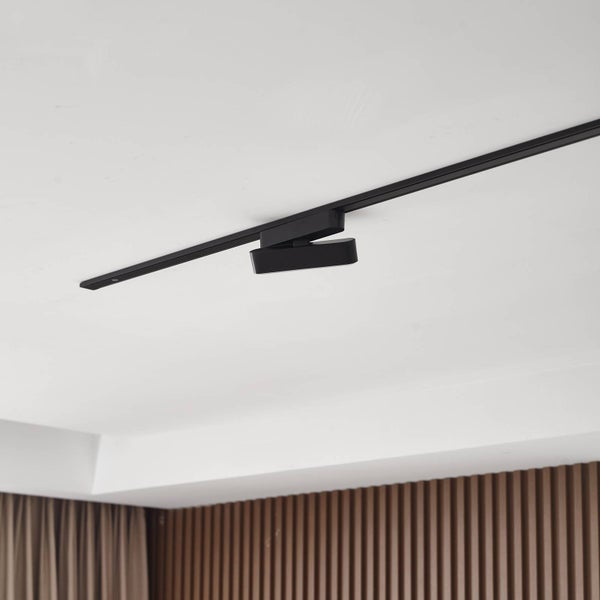 Schwarze Stromschiene mit rechteckigem LED Strahler an einer weißen Decke montiert.