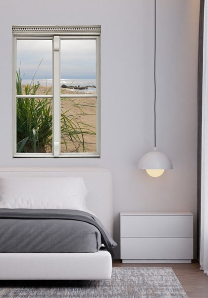 Modernes Schlafzimmer mit Bett, Nachttisch, Hängelampe und Fenster zum Strand