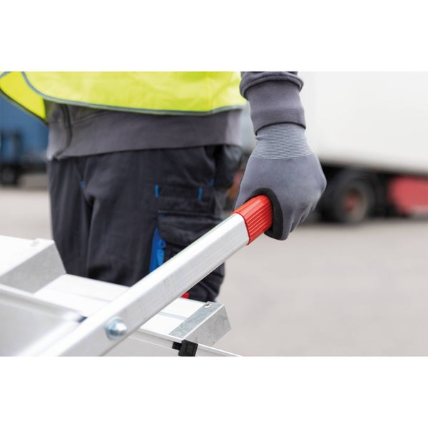 Eine Person in Arbeitskleidung hält eine Aluminiumleiter mit rotem Griff.