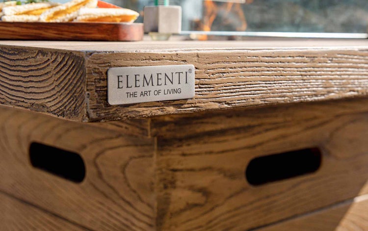 Detailansicht eines Feuertisches in Holzoptik mit Elementi Logo.