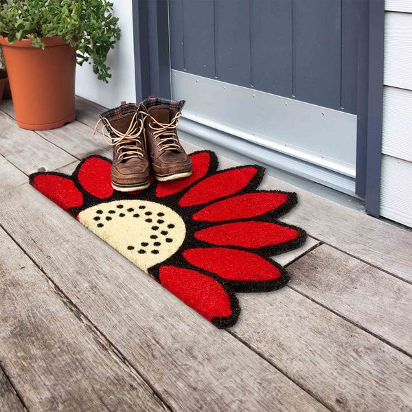 Fußmatte mit Blumenmuster vor einer Haustür mit Schuhen.