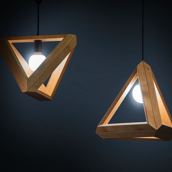 Zwei geometrische Pendelleuchten aus Holz in Dreiecksform mit sichtbaren Leuchtmitteln.