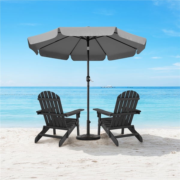 Zwei Holzstühle unter einem Sonnenschirm am Strand