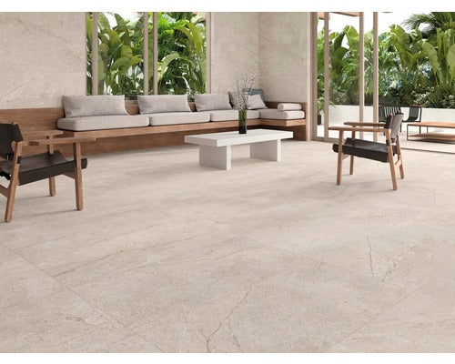 Heller Wohnraum mit Bodenfliesen, Sitzgelegenheiten und tropischen Pflanzen vor dem Fenster