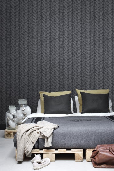 Raumansicht mit Strickmuster Tapete, Bett auf Holzpaletten und dekorativen Elementen