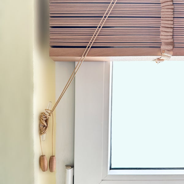 Holzjalousie am Fenster mit Zugschnüren und Bedienknöpfen