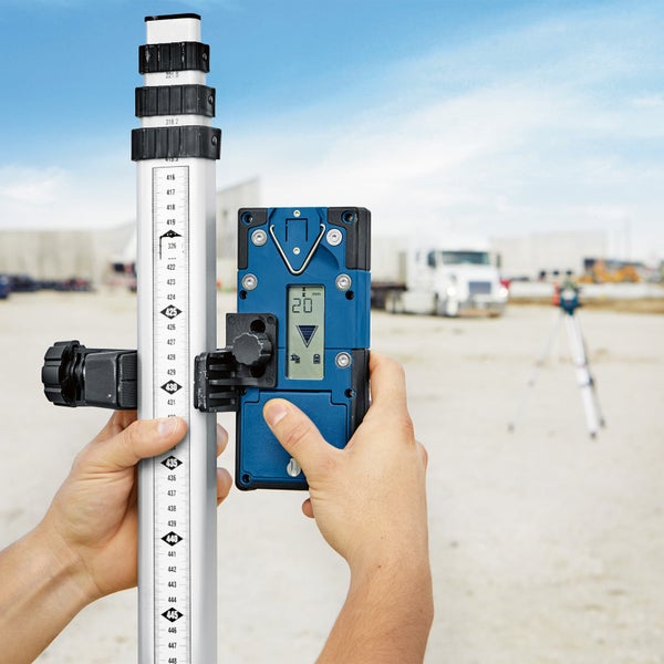Eine Person hält eine Nivellierlatte mit Digitalanzeige.
