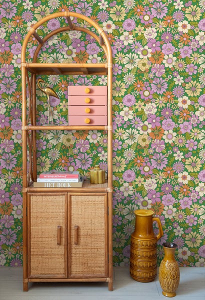 Szene mit Blumendesign Tapete, Regalsystem aus Rattan, Dekorationsobjekten und Vasen