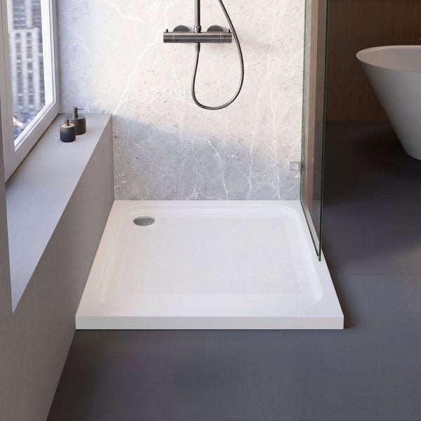 Rechteckige weiße Duschwanne in flacher Bauweise in einem modernen Badezimmer mit Glasabtrennung und marmorierter Wand.